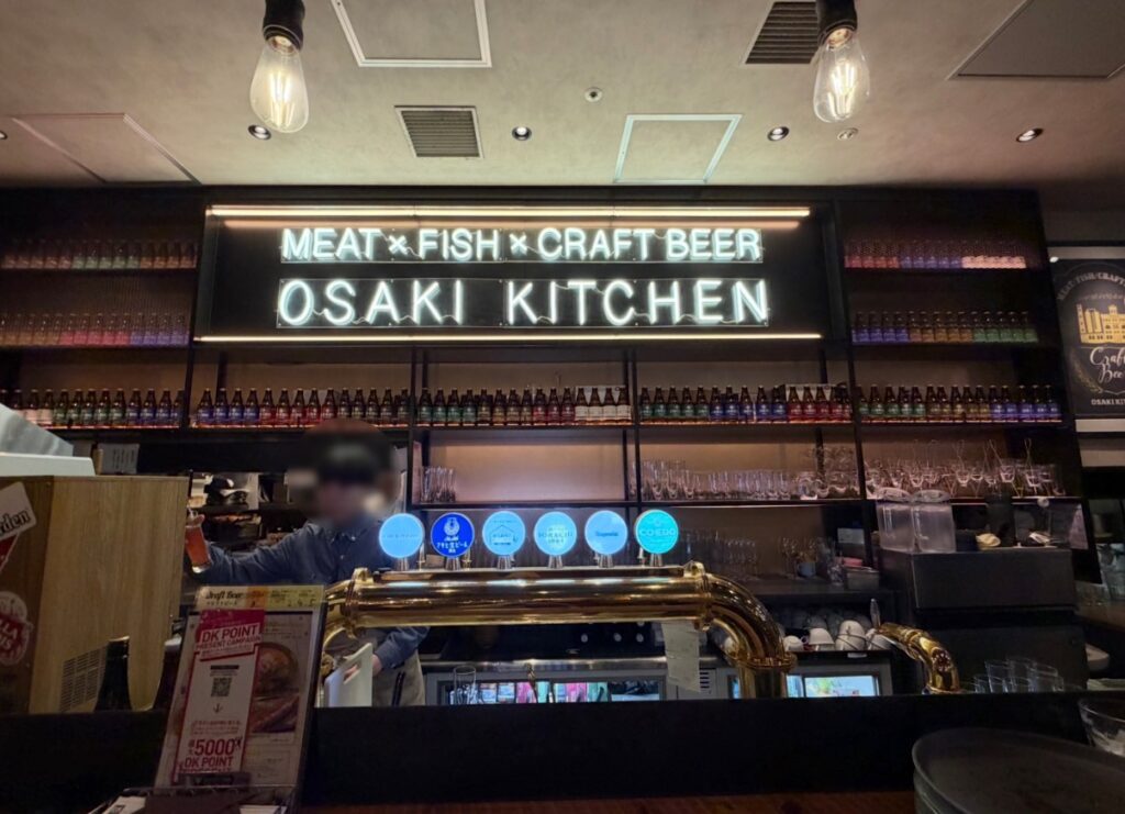 大崎キッチン（OSAKI KITCHEN）のカウンター席から見た店内の様子。クラフトビールのサーバーとバーカウンターが並び、目の前でドリンクを作るライブ感のある雰囲気が伝わる写真。