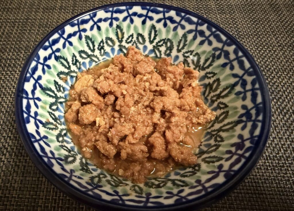 ゆうちょ銀行の株主優待で届いた築地魚河岸「希缶」シリーズのまぐろ親子煮を器に盛り付けた写真。そぼろ状のまぐろの身と卵が甘辛いタレに絡み、和食の小鉢にたっぷり盛られている様子。
