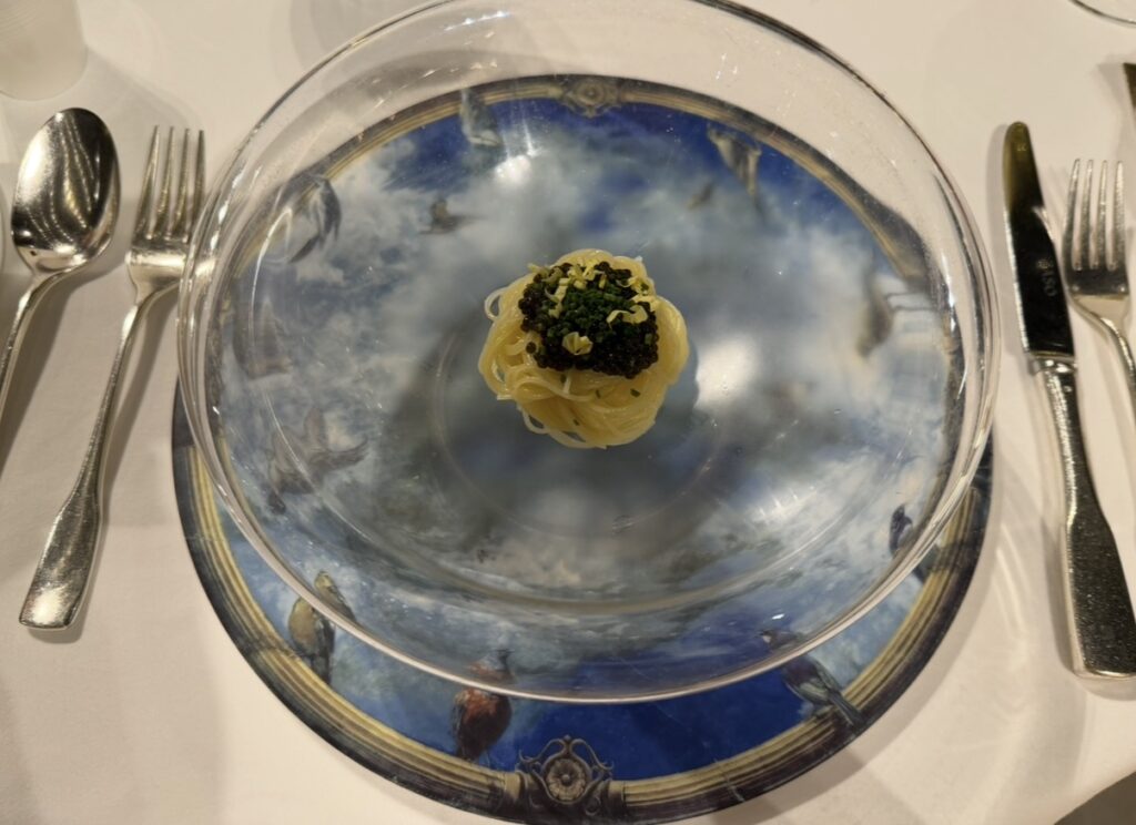 リストランテASOのクリスマスディナーで提供された前菜、キャビアの冷製カペリーニ。天井画「碧空」と同じモチーフのプレートの上に、ガラスの器で美しく盛り付けられた一皿。
