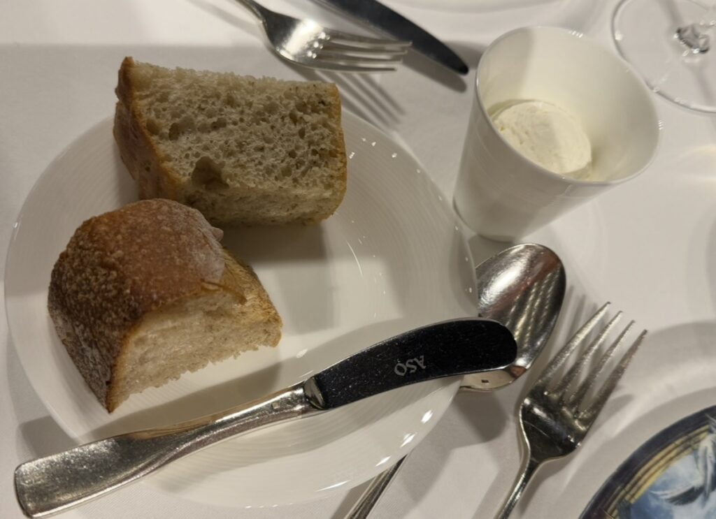 クリスマスディナーで提供された焼きたてのパンとバター。ふんわりとしたパンと上質なテーブルウェアが並ぶ、コース序盤のひとコマ。
