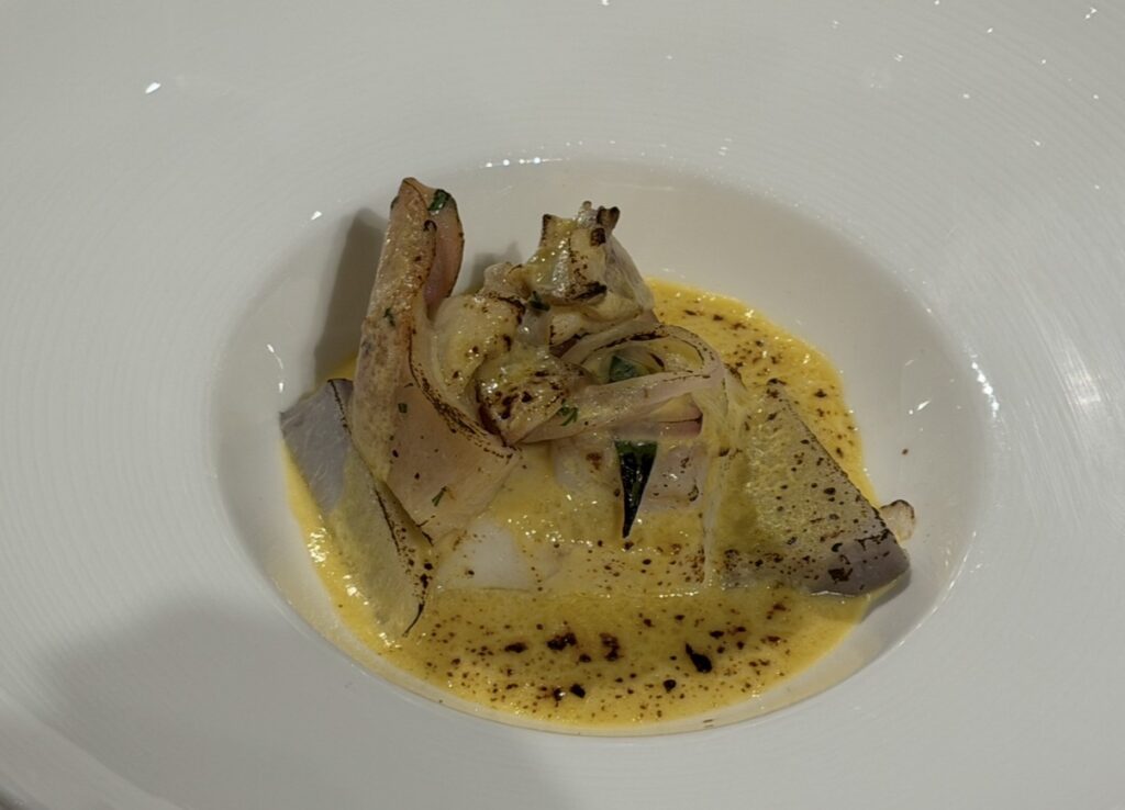 ヒラメの白ワイン蒸しに北寄貝と海老芋を添えた一皿。白いプレートに盛り付けられた上品な魚料理の写真。
