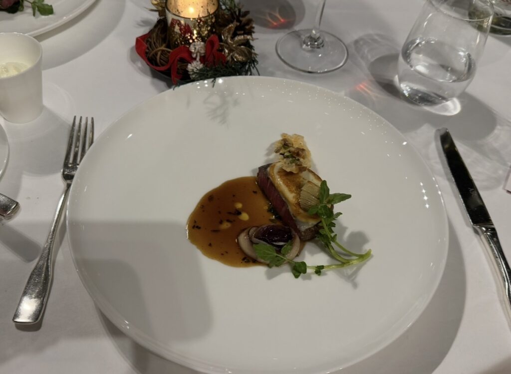 スカモルツァチーズを纏った和牛ヒレ肉のローストに、ジャガイモのスフォリアテッラと寒締めほうれん草を添え、トリュフ香るスーゴディカルネをかけたメインディッシュの写真。
