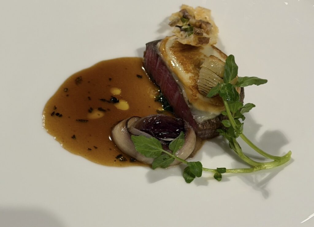 スカモルツァチーズをのせた和牛ヒレ肉のローストに、トリュフ香るスーゴディカルネを添えたメインディッシュのアップ写真