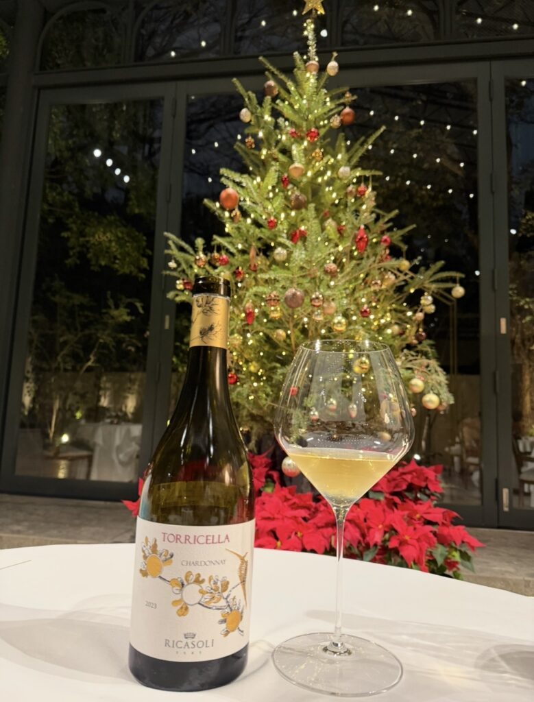 リカーゾリ「トッリチェッラ シャルドネ」とワイングラスをテーブルに置き、背景にクリスマスツリーが輝くペアリング6杯目の写真。
