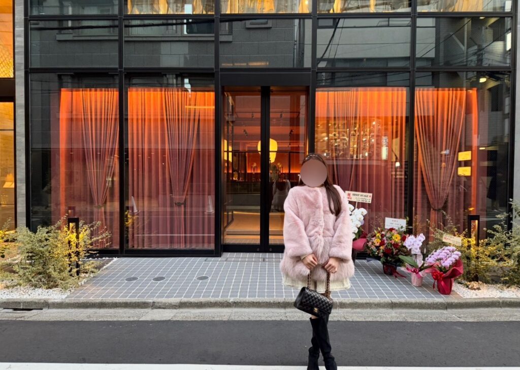 恵比寿にオープンしたひらまつの新店舗「HRMT STAGE」の店頭外観。ガラス張りのファサードと暖色の照明が印象的で、オープン初日のお祝い花が並ぶレストラン入口の様子。