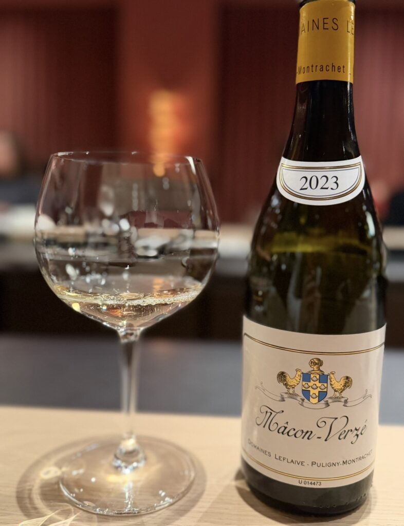 ひらまつ新店舗「HRMT STAGE」のワインペアリングで提供された、ドメーヌ・ルフレーヴの白ワイン「マコン・ヴェルゼ 2023」。グラスとボトルがカウンター席に並んでいる。