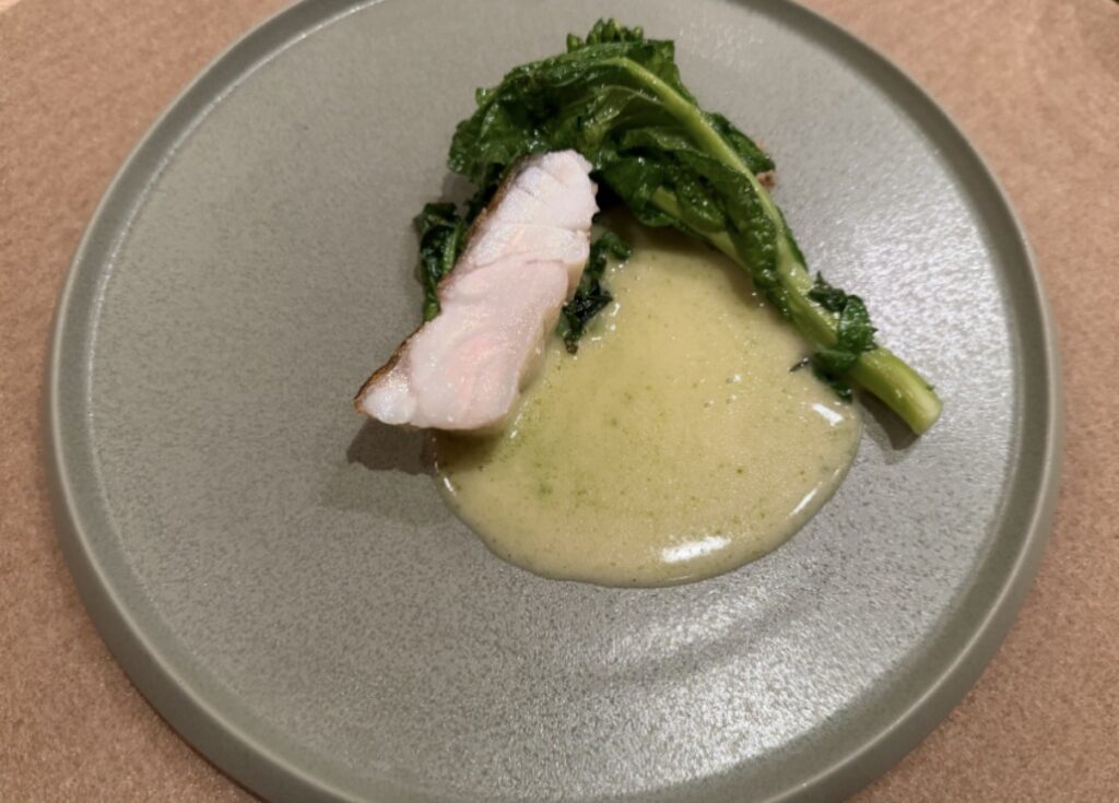 ひらまつ新店舗「HRMT STAGE」のコース料理、長崎県産おおもうはたのポワレに、クルミのブールブランソースとディルオイルを合わせた一皿。付け合わせの青菜とともに盛り付けられている。
