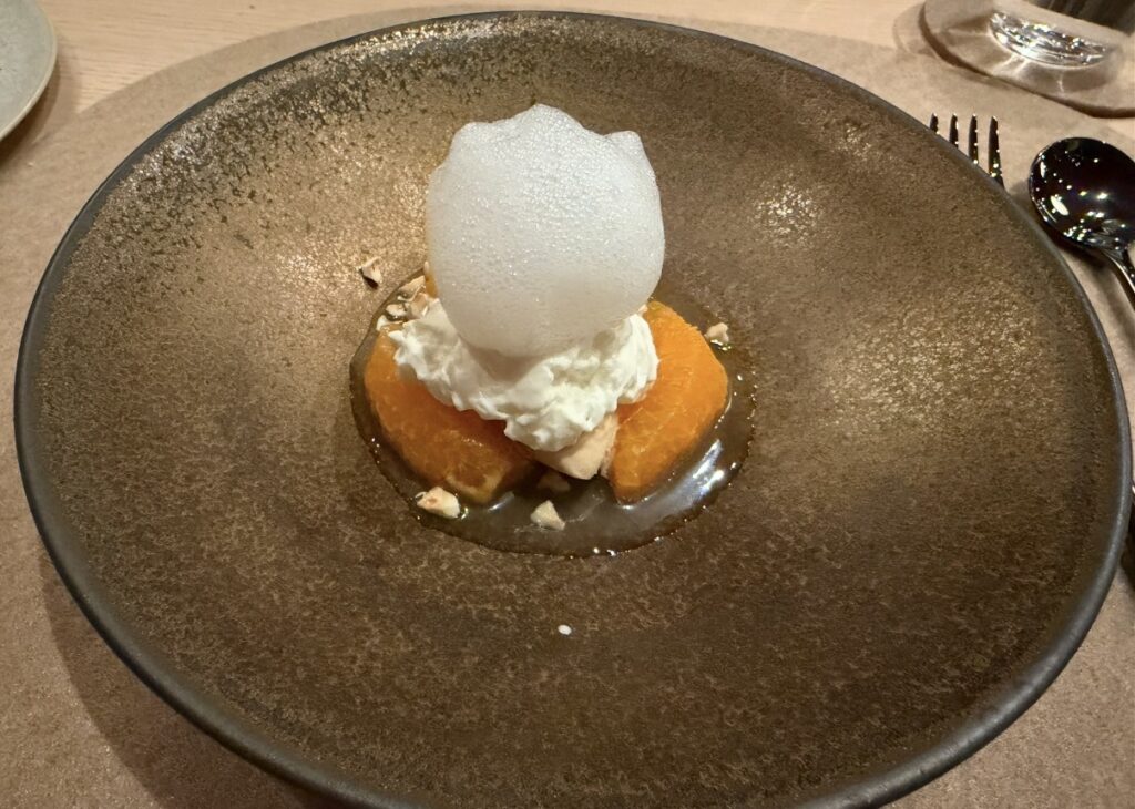 フキノトウの泡をのせたデザート「プラリネのアイスとかんきつ、フロマージュブラン」を盛り付けたひらまつのコースデザート