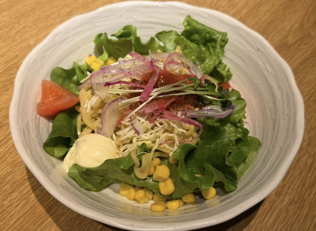 北の味紀行と地酒 北海道で注文した北海道名物のラーメンサラダ。レタスやトマト、コーンなどの野菜とラーメンが盛り付けられた一皿