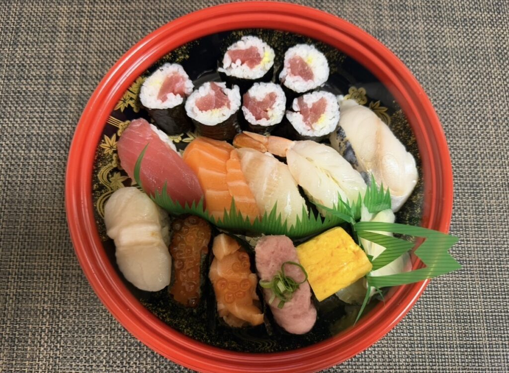 銀のさらで注文した寿司セットが自宅に届いた様子の写真。マグロ、サーモン、エビ、ホタテ、いくらなどが桶に美しく盛り付けられている