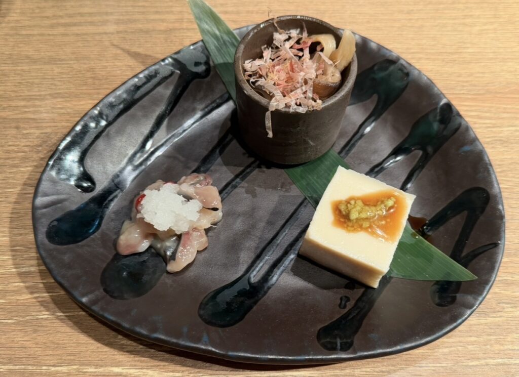 ハタハタ屋敷 有楽町のコース料理の前菜3種。茸の焼き浸し、胡麻豆腐、鰊の切込みが盛り付けられた前菜プレート。