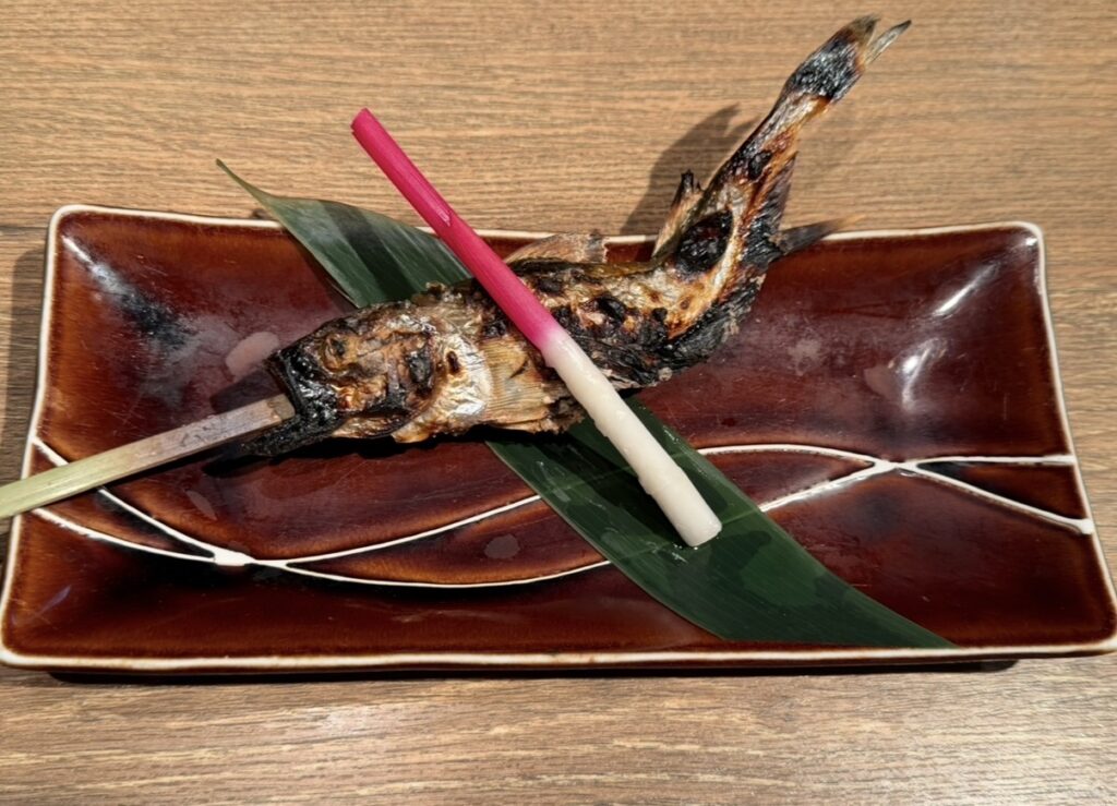 ハタハタ屋敷 有楽町のコース料理「ハタハタ焼き（雄）」。串に刺して香ばしく焼き上げた秋田名物ハタハタの焼き魚。
