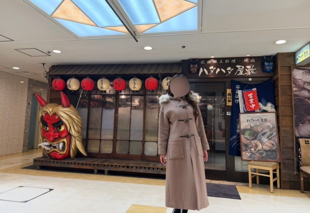 秋田郷土料理店「ハタハタ屋敷 有楽町」の店舗前にある大きななまはげ像と提灯の装飾、入口前で撮影したブログ運営者COCOの写真（※顔はぼかしを入れて掲載しています）