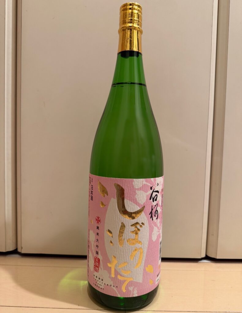 ベルーナ株主優待で届いた日本酒「谷櫻 しぼりたて純米大吟醸」の一升瓶。ピンク色のラベルが特徴の日本酒。