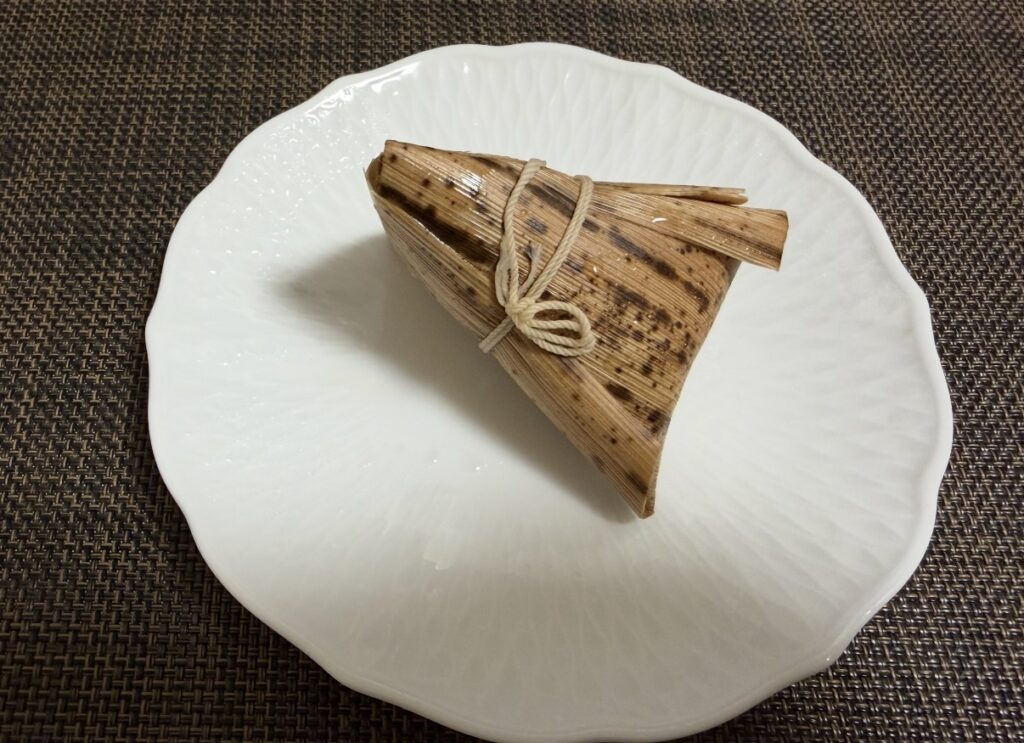 竹の皮に包まれた中華ちまきが皿にのせられている様子