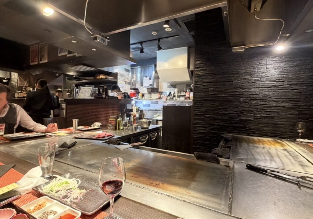 銀座のステーキの店内カウンター席の様子。鉄板を囲むライブキッチンで目の前でステーキを焼いてもらえる落ち着いた雰囲気の空間