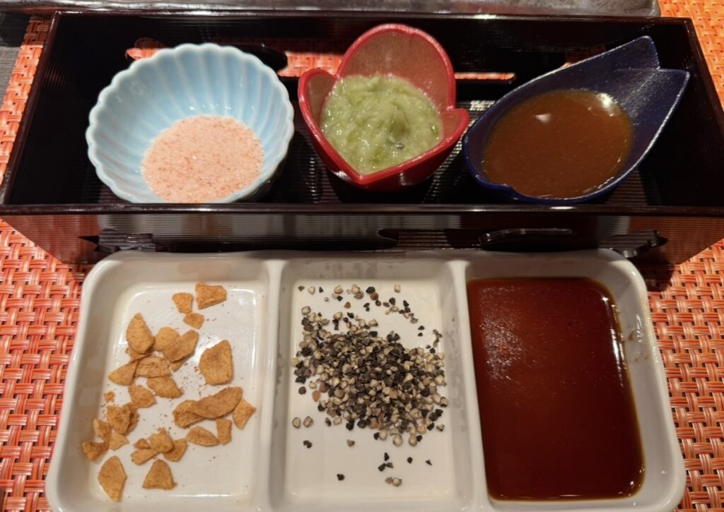 銀座のステーキ銀座本店で提供された薬味セット。ガーリックチップや黒胡椒、醤油に加え、ヒマラヤ岩塩やわさび、ウニ醤油が並び、さまざまな味でステーキを楽しめる構成になっている