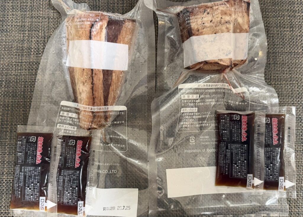日本管財HDの株主優待で届いた一本釣り鰹炭火焼たたき2本と専用たれ4袋の写真。