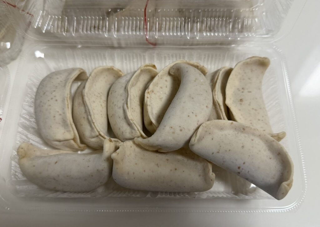 肉汁餃子のダンダダンで購入した冷凍生餃子のアップ写真。厚みのある大ぶりな餃子がパックに並べられている。