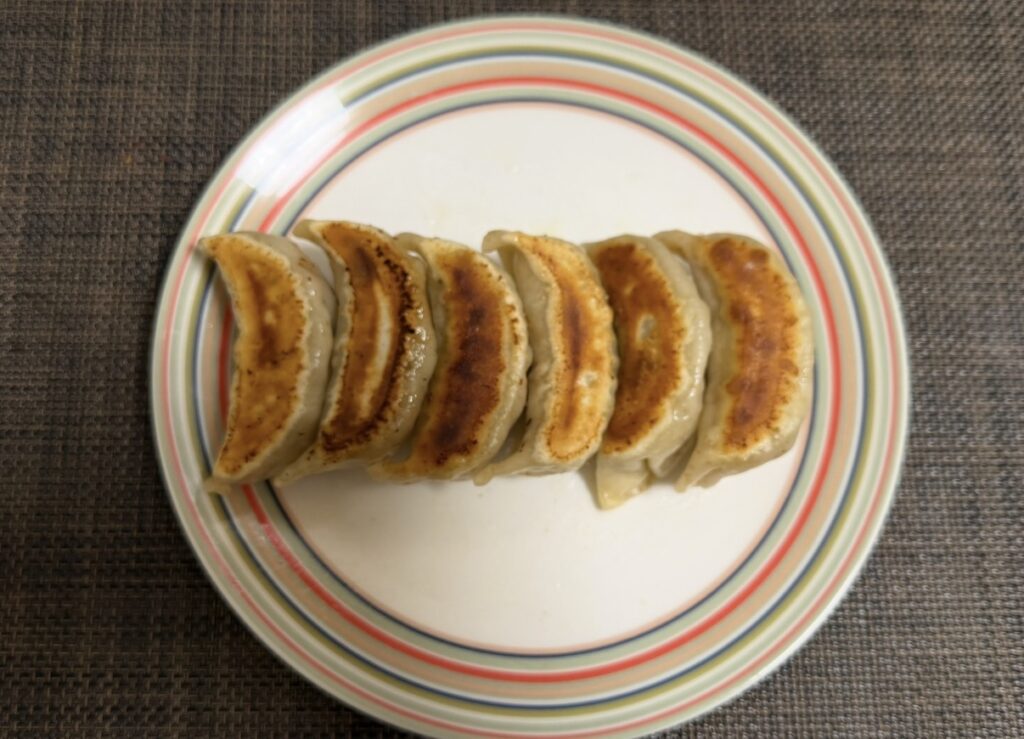 肉汁餃子のダンダダンで購入した冷凍生餃子を自宅で焼いた様子。こんがり焼き色が付いた大ぶりな餃子が皿に並べられている。
