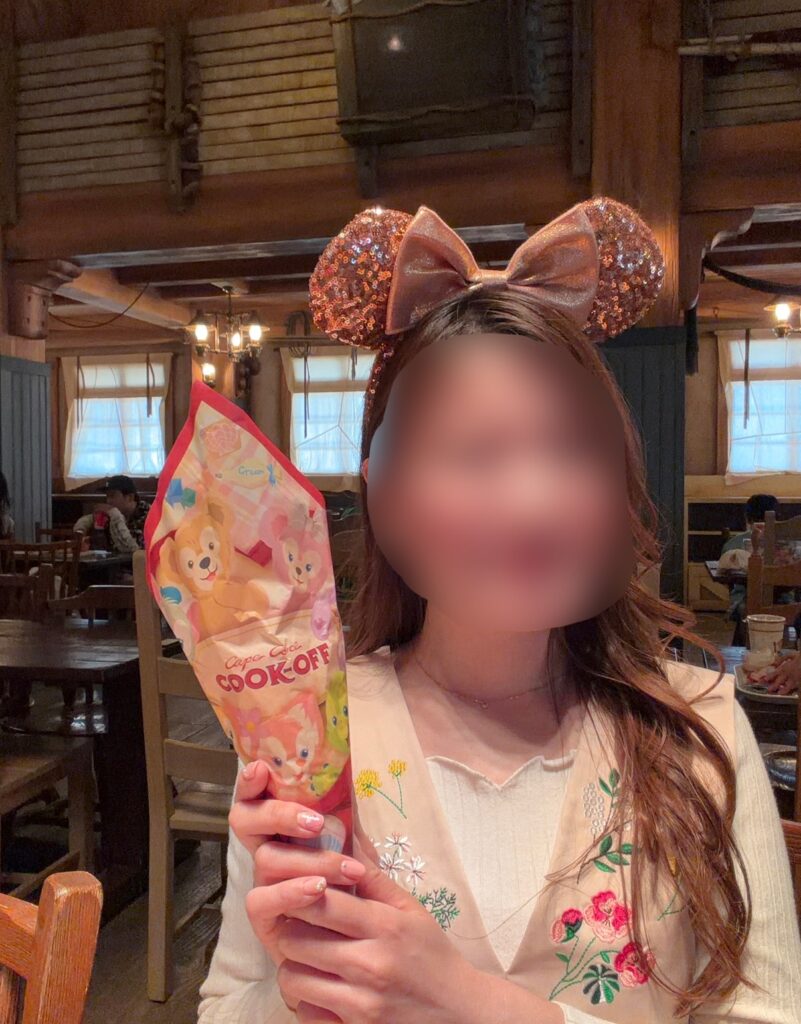 ブログ運営者COCOが東京ディズニーシー「ケープコッド・クックオフ」のダッフィー&フレンズデザインのトルティーヤサンドの包み紙を手に持って記念撮影している様子。店内でランチを楽しんでいる写真。