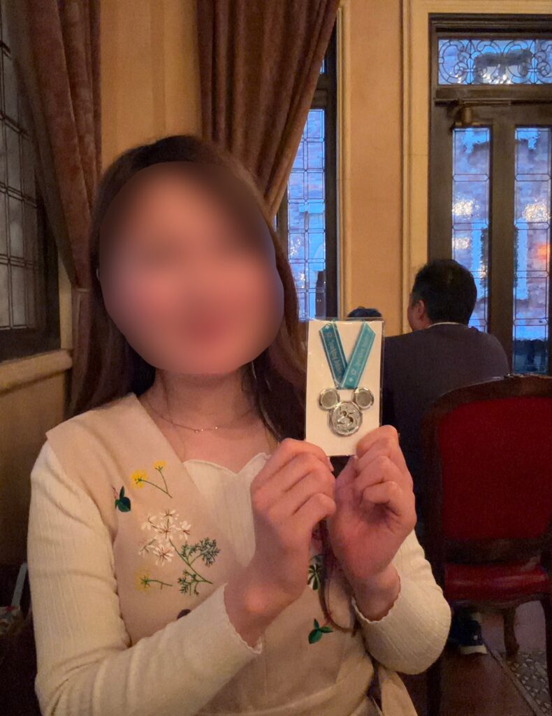 東京ディズニーシー25周年のスーベニアメダルを手にした記念写真。リストランテ・ディ・カナレットで購入した25周年限定の記念品とともに、特別な一日の思い出を残した一枚。