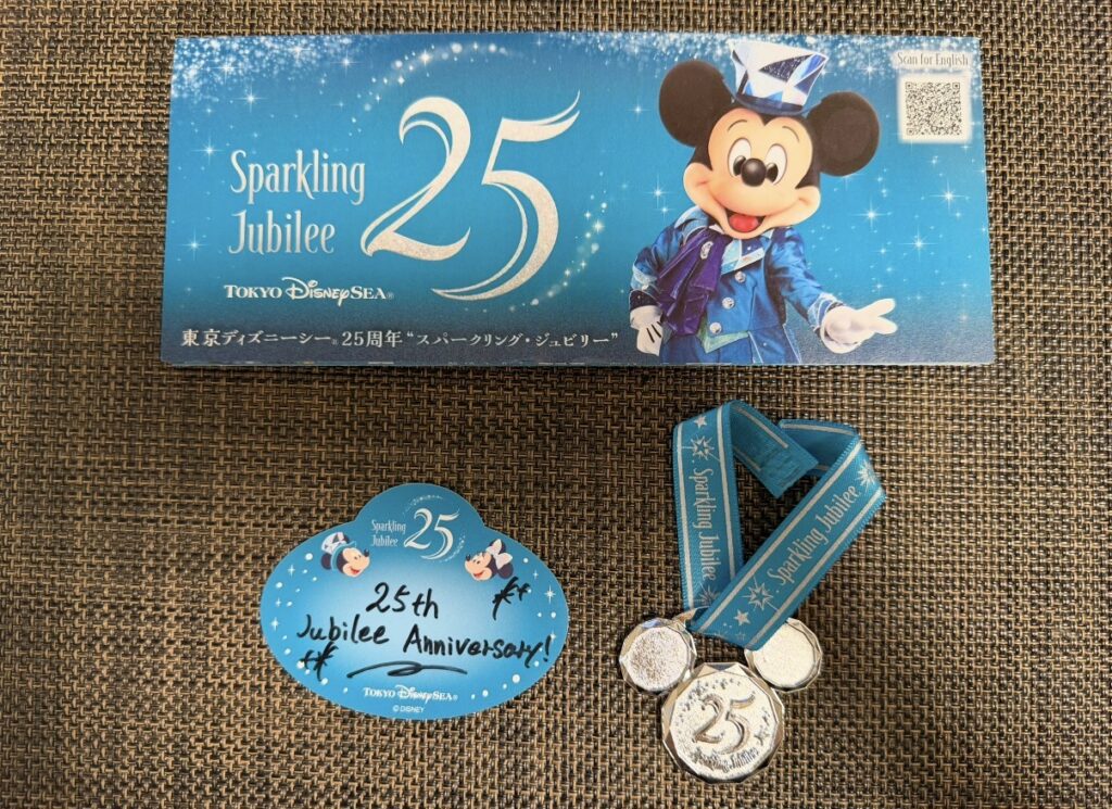 東京ディズニーシー25周年「スパークリング・ジュビリー」のリーフレット、ジュビリーシール、25周年限定スーベニアメダル。実際に集めた記念グッズを紹介した写真。