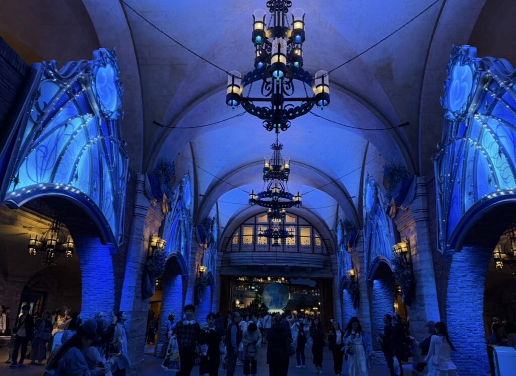 夜のライトアップに包まれた東京ディズニーシー25周年の装飾。ジュビリーブルーに彩られた幻想的なアーチとシャンデリアが美しく輝く、閉園前の特別な雰囲気を撮影した一枚。