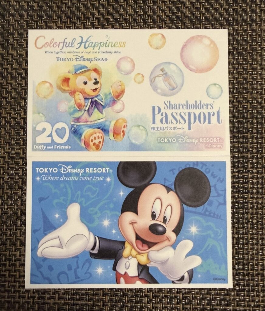 OLC創立65周年記念チケット(上)と2025年通常デザインの株主優待パスポート(下)を並べて比較した写真。上はダッフィー&フレンズ20周年デザイン、下はミッキーマウスデザインの東京ディズニーリゾート株主用パスポート。