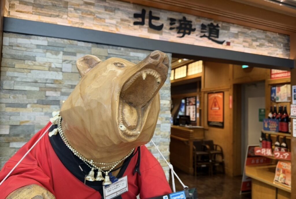 北の味紀行と地酒 北海道の店舗入口と大きな木彫りの熊のオブジェ。